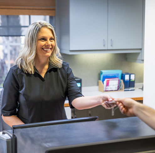 Man shakin hands with dental team member after submitting his dental insurance forms