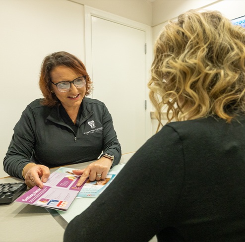 Man shakin hands with dental team member after submitting his dental insurance forms