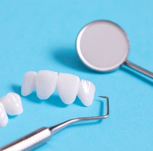 Dental bridges and dental tools against a blue background