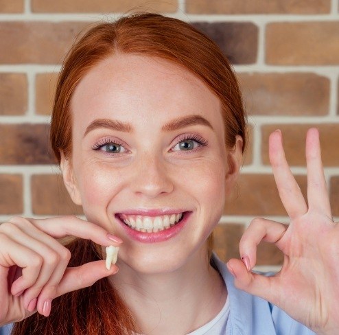 Woman holding up tooth after wisdom tooth extraction