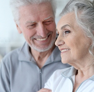 Older couple smiling together with sweaters on