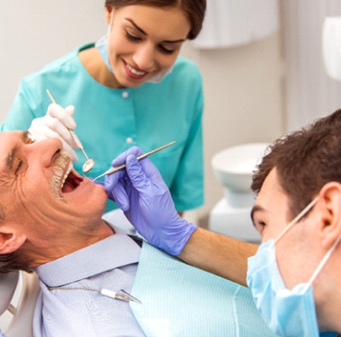 Dentist examining a patient considering implant dentures in Port Charlotte