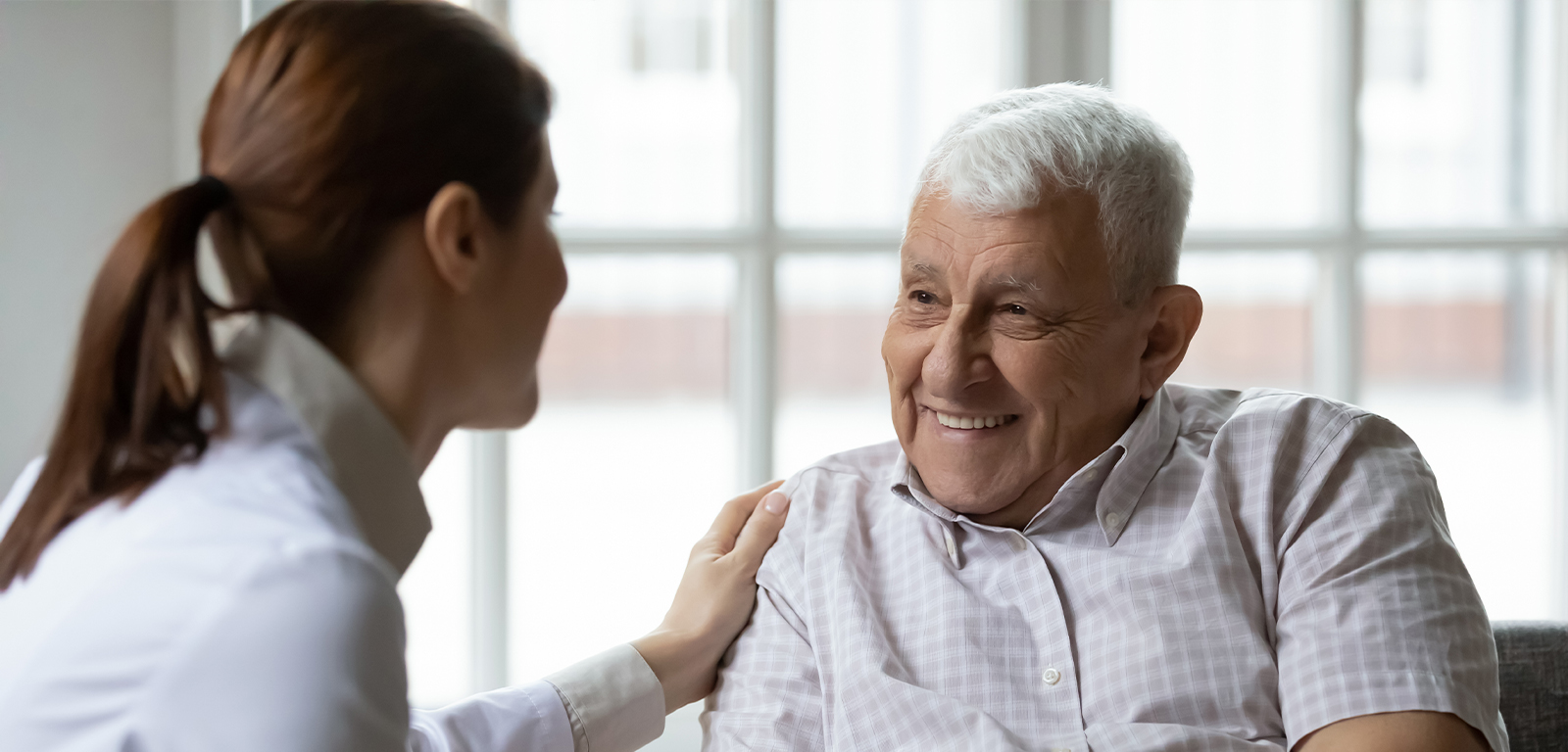 Dental team member talking to senior man and resting her hand on his shoulder