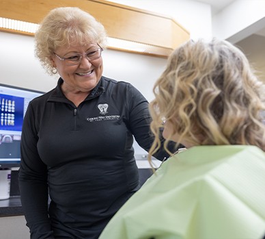 Woman looking at close up of smile on tablet screen in dental chair