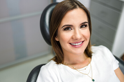 Young woman in white t shirt smiling in dental chair