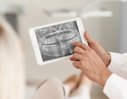 Dentist pointing to digital x-rays on tablet computer