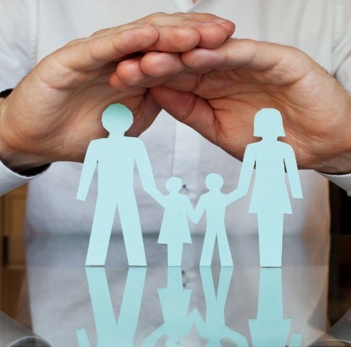 Hands protecting a paper cutout family