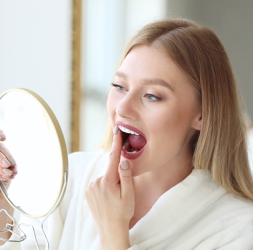 Patient in Port Charlotte looking in the mirror at their dental implants