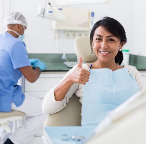 Woman giving thumbs up after oral surgery