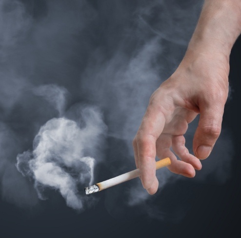 Person smoking cigarettes increasing risk for gum disease