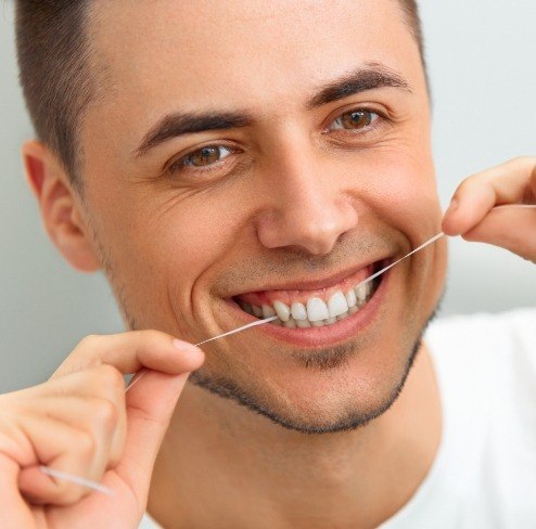 Man flossing teeth to prevent gum disease