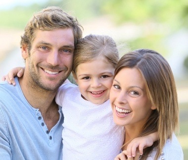 Family of three smiling after preventive dentistry visit