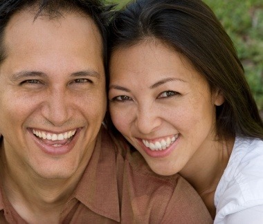 Man and woman with healthy smiles after gum disease treatment