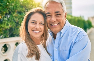 Man and woman with healthy smiles after replacing missing teeth