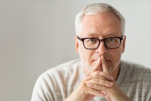 Man with glasses with hands on face thinking