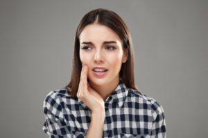 Woman in plaid with hand on cheek due to jaw pain