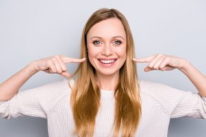 Woman smiling while pointing to her teeth