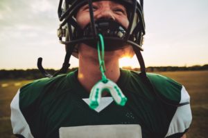 Boy playing football with mouthguard attached to face mask