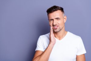 Man with hand on his cheek due to dental pain