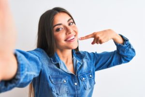 Woman smiling while pointing to her smile