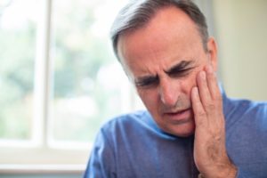 Man with hand on face due to jaw pain