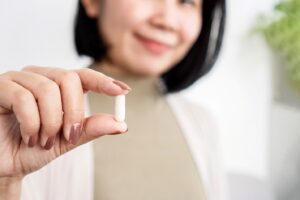 Woman holding probiotic pill.
